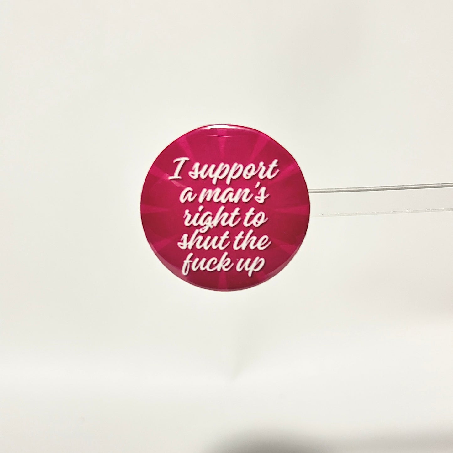 finback button with white text saying I support a man's right to shut the fuck up with two toned pink background