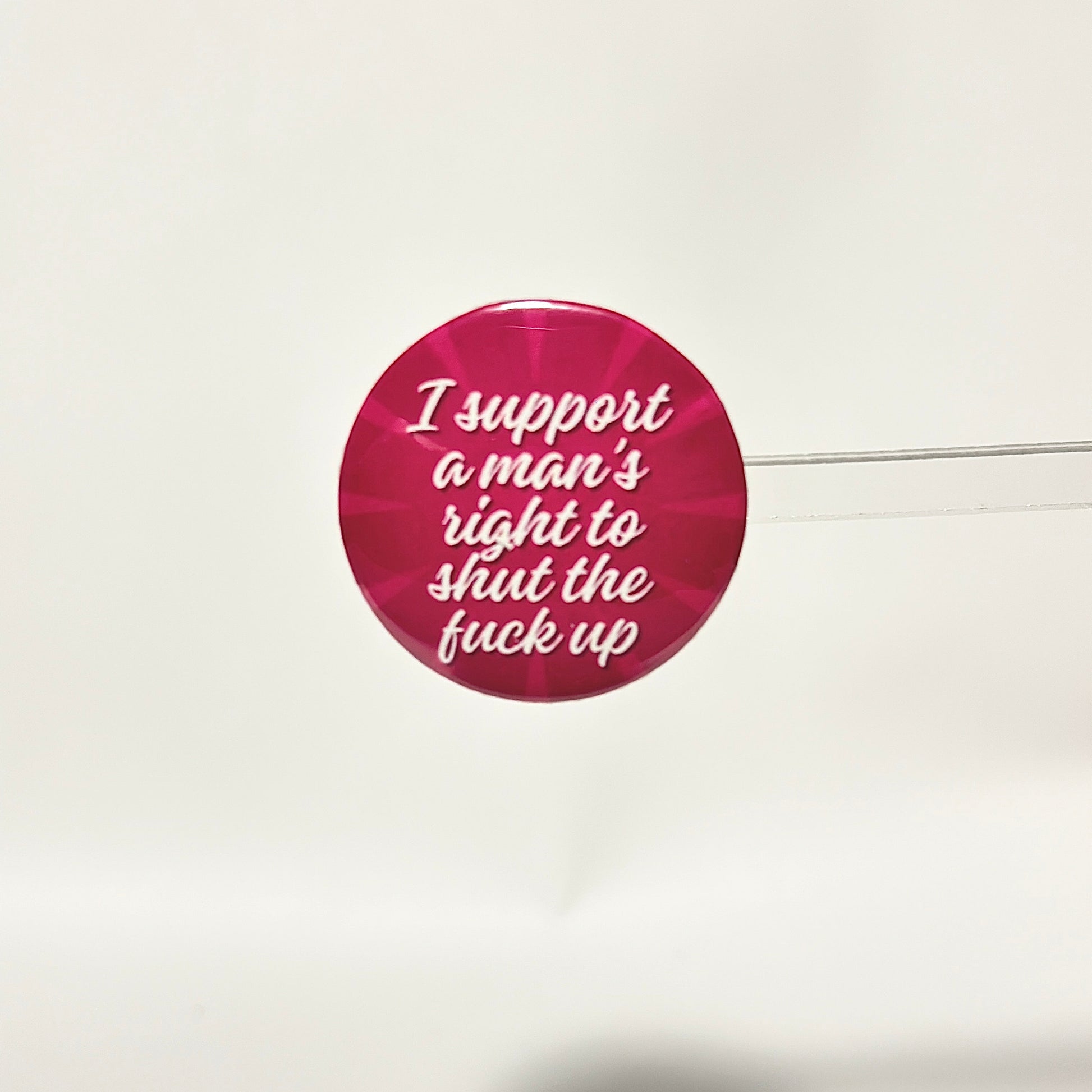 finback button with white text saying I support a man's right to shut the fuck up with two toned pink background